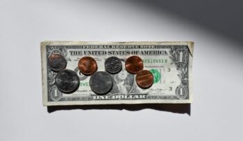 A dollar bill with assorted coins on top of it|sharon mccutcheon unsplash