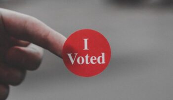 A person holding a sticker that says "I Voted"|loren joseph unsplash