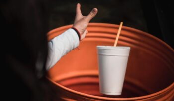 A woman throwing a styrofoam cup away|caleb lucas unsplash