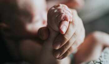 Baby and mother holding hands