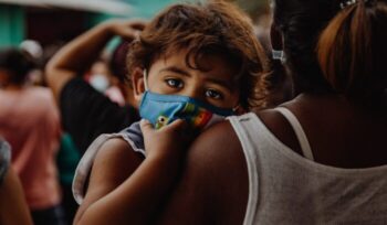 Child with mask in adult's arms