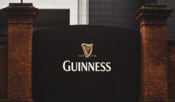 Guiness logo on a large gate|louis hansel unsplash