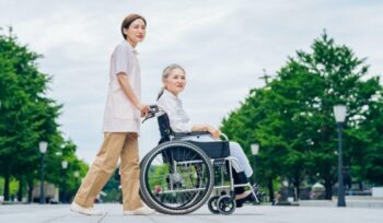 Japanese woman pushing another in wheelchair