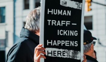 Man holding "Human trafficking happens here" sign|eunice stahl unsplash