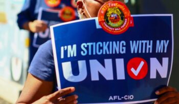 Person holding "I'm sticking with my union" sign