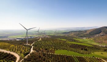 Wind turbines across a green landscape|ethan weil unsplash