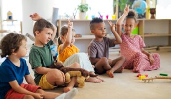 Children in preschool raising their hands